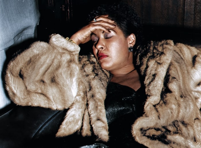 Billie Holiday sitzt mit geschlossenen Augen auf einer Leder Couch / Sofa -